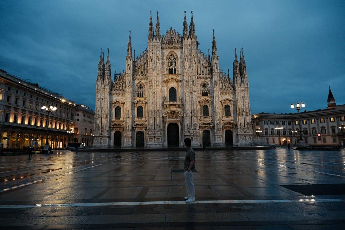 Brendan standing in the nearly empty piazza before the Milan Duomo at dusk