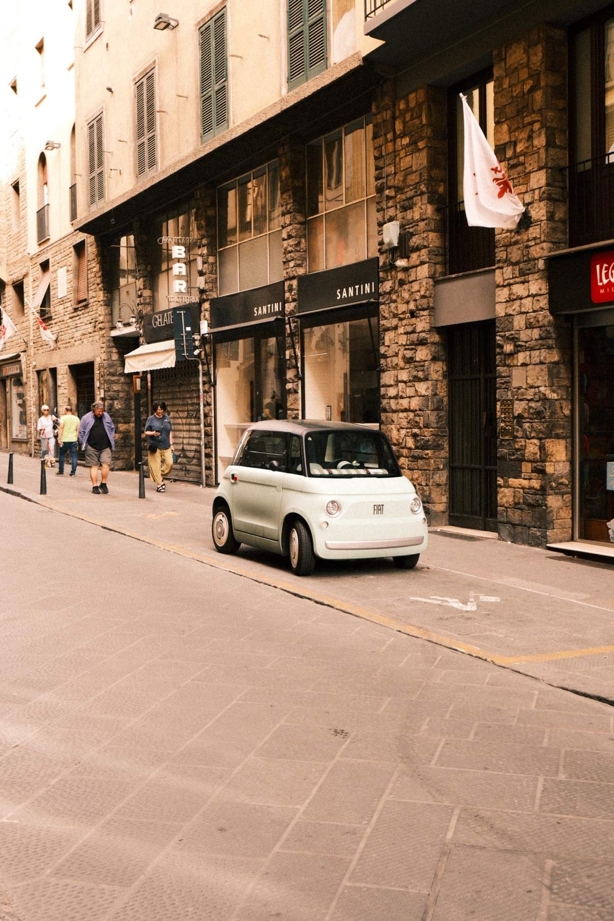 A small cream Fiat Topolino parked on a stone street in Florence