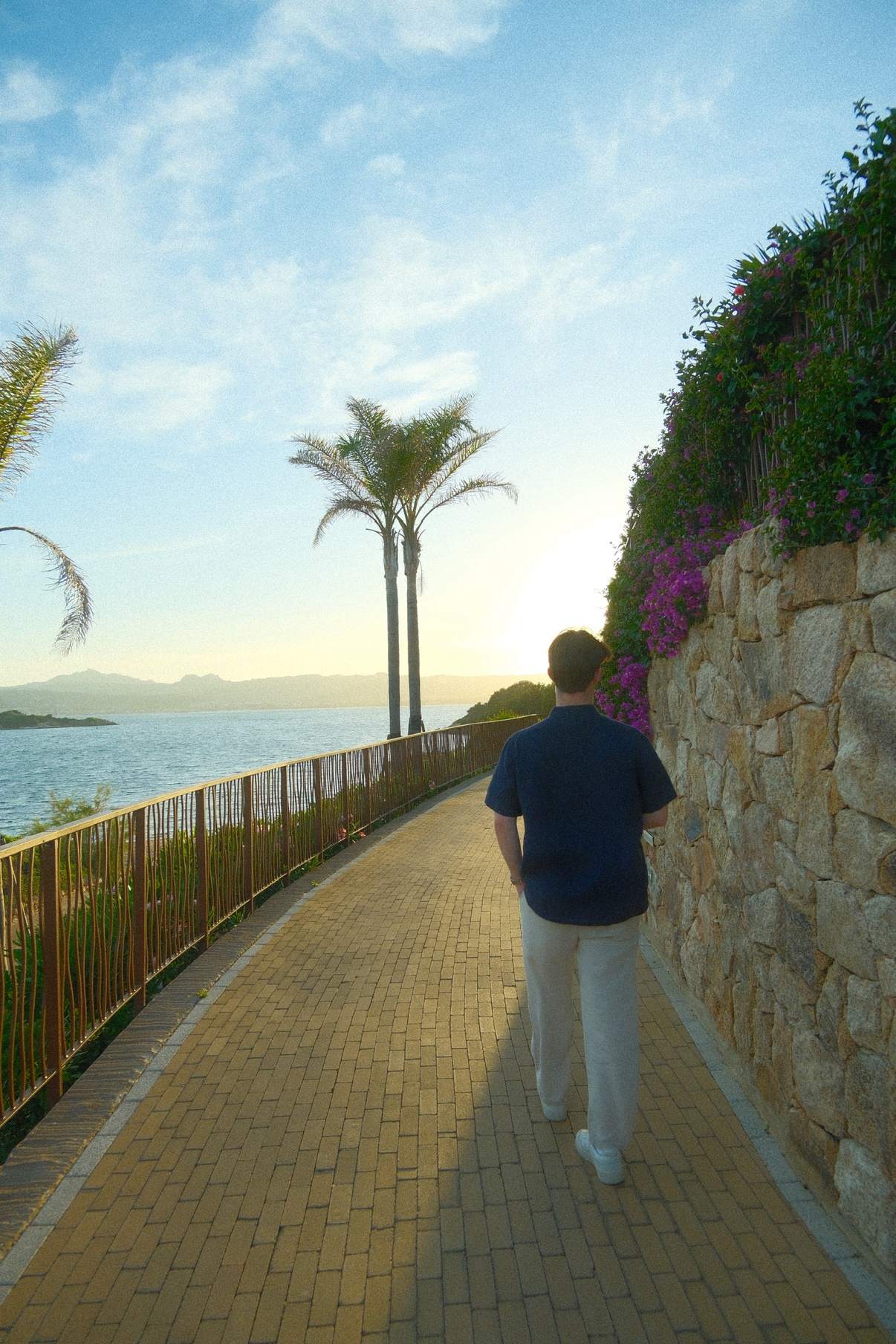 Brendan walking a waterfront promenade in Sardinia as the sun sets